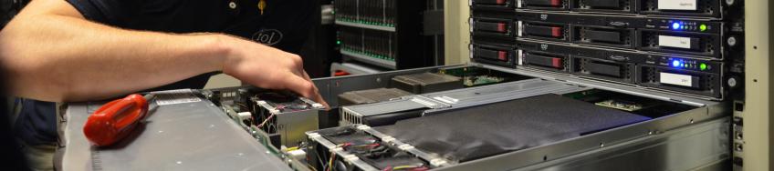 person adding computer equipment to an open drawer in a server rack